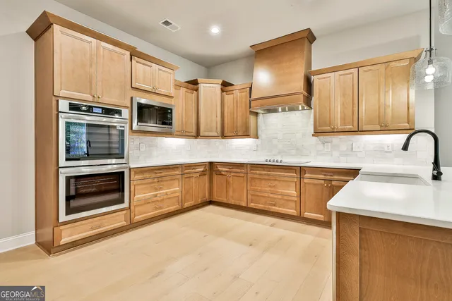 a large kitchen with granite countertop a large counter top stainless steel appliances and cabinets