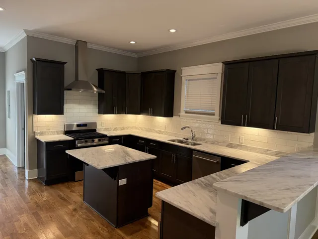 a kitchen with granite countertop a sink dishwasher a stove and a refrigerator with wooden cabinets