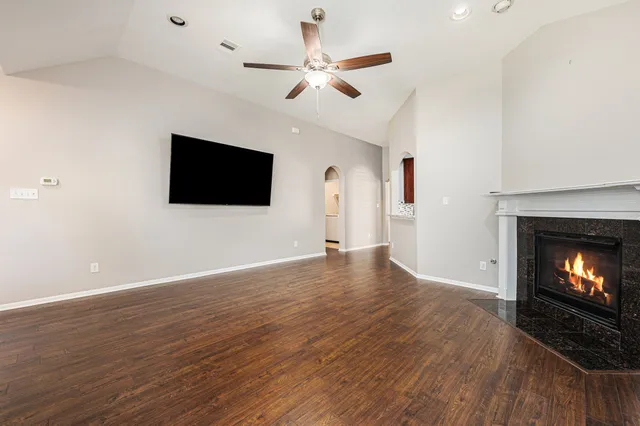 a view of a livingroom with a fireplace a ceiling fan and wooden floor