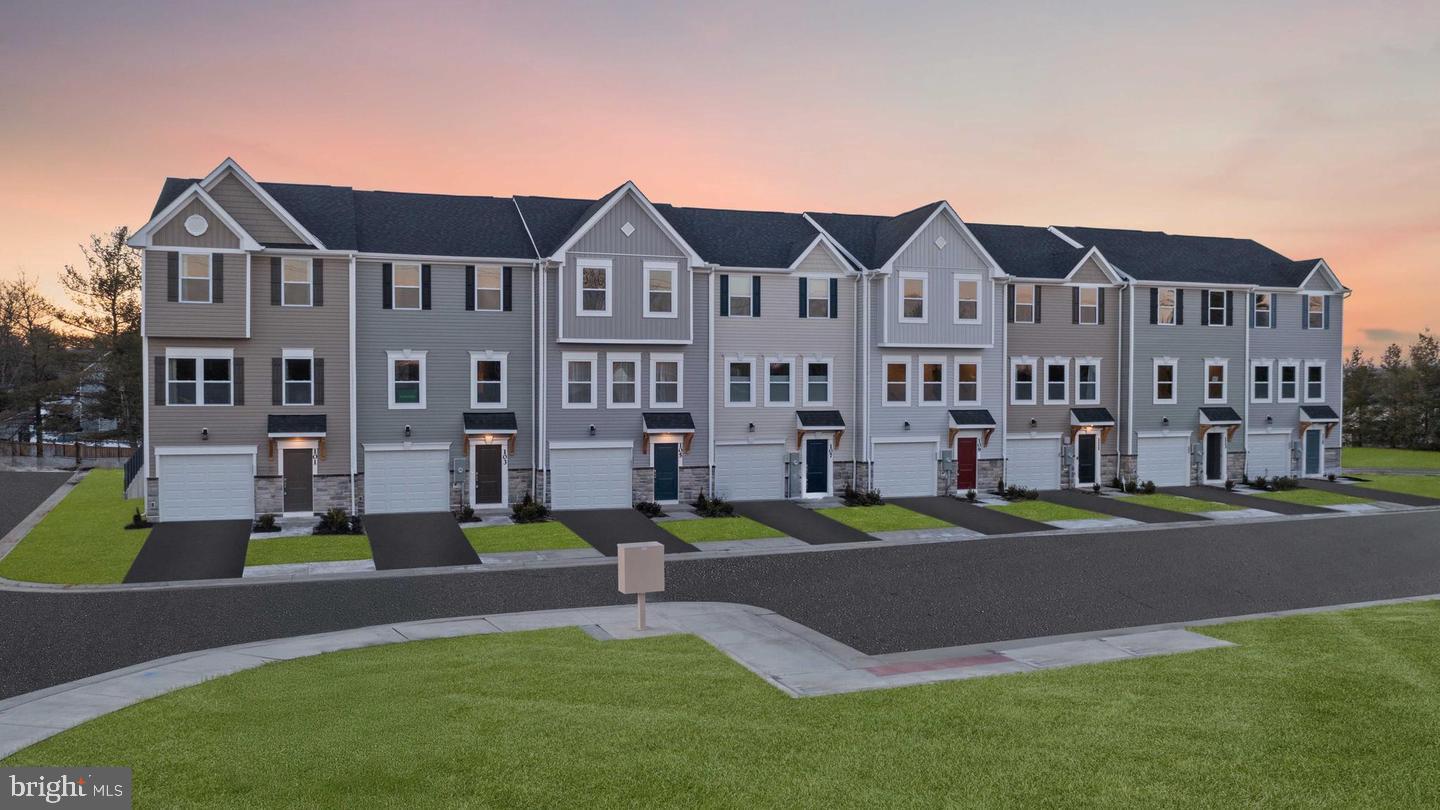 a front view of a building with garden and trees