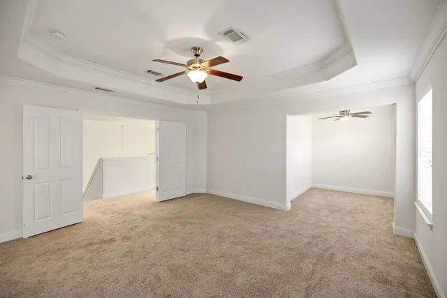 an empty room with chandelier fan and windows