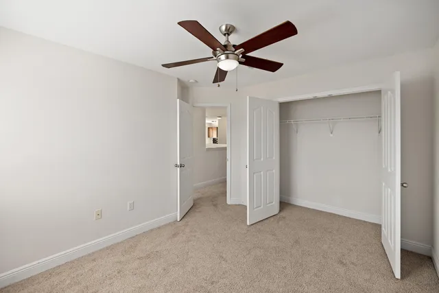 an empty room with ceiling fan and windows