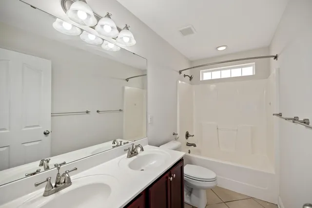 a bathroom with a double vanity sink toilet mirror and shower