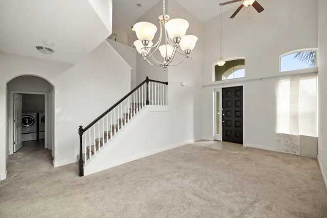 a view of an empty room with a chandelier fan and a window
