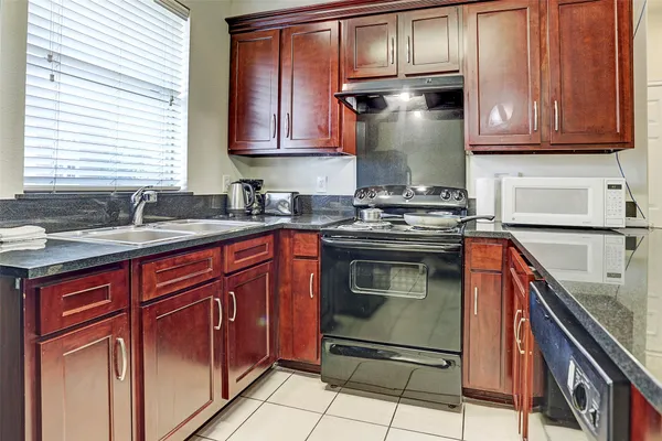 a kitchen with granite countertop a sink stove and cabinets