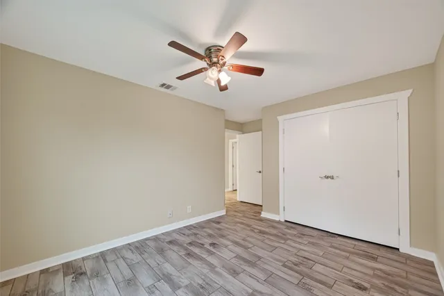 a view of empty room with wooden floor and fan