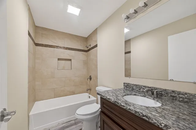 an empty room with wooden floor ceiling fan and windows