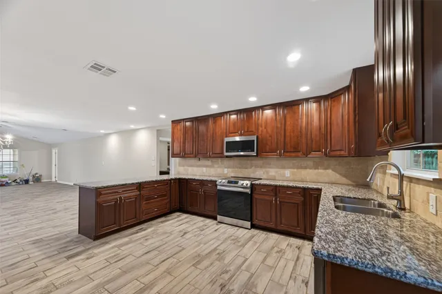 a kitchen with stainless steel appliances granite countertop wooden cabinets a stove top oven a sink and dishwasher