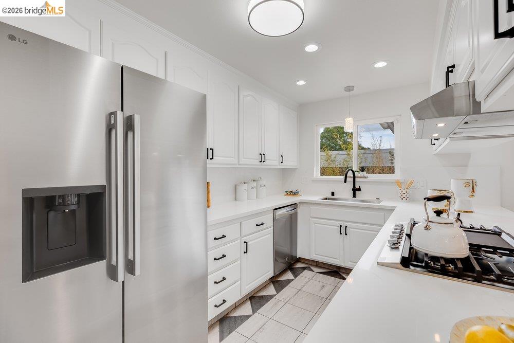 1298 Ribbon Street Foster City, CA 94404 - Photo 31 of 86 Modern kitchen featuring stainless steel appliances, white cabinetry with black hardware, white countertops, and a distinct black and white floor tile pattern
