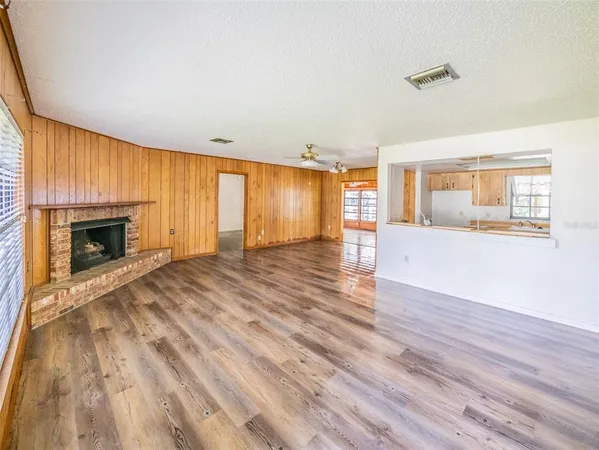 an empty room with wooden floor fireplace and windows