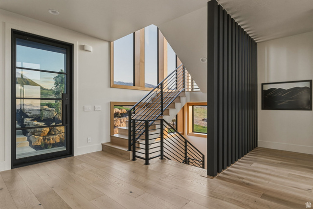 923 North Emery Lane Elk Ridge, UT 84651 - Photo 7 of 101 Contemporary entryway featuring a black-framed glass entry door, light wood-finish flooring, and a multi-level staircase with metal railings