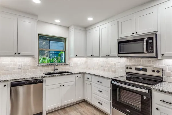 a kitchen with granite countertop white cabinets stainless steel appliances and a sink