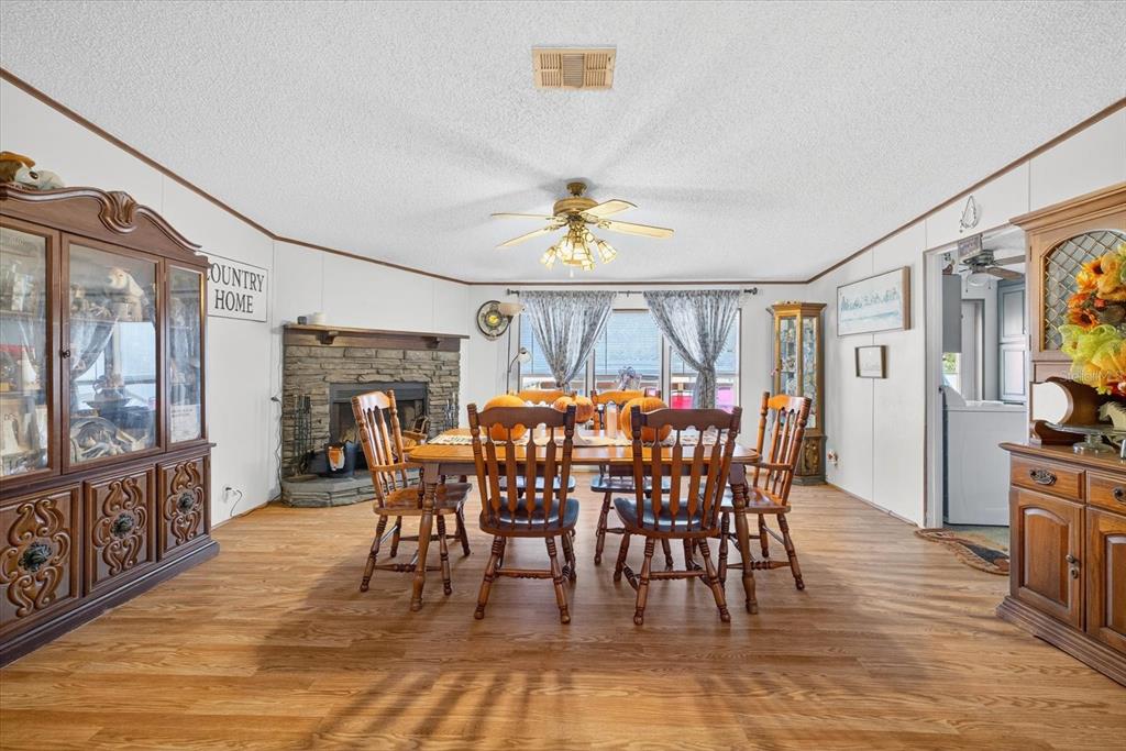 5280 Golddust Road Spring Hill, FL 34609 - Photo 13 of 41 a view of a dining room and livingroom with furniture wooden floor a rug a flat screen tv a painting and a chandelier