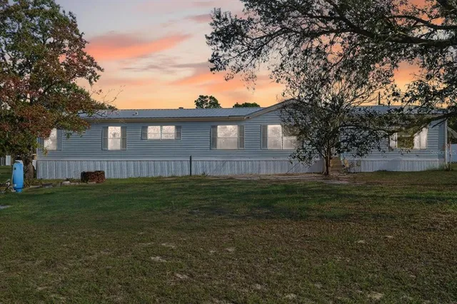 a brick house next to a yard with a large tree