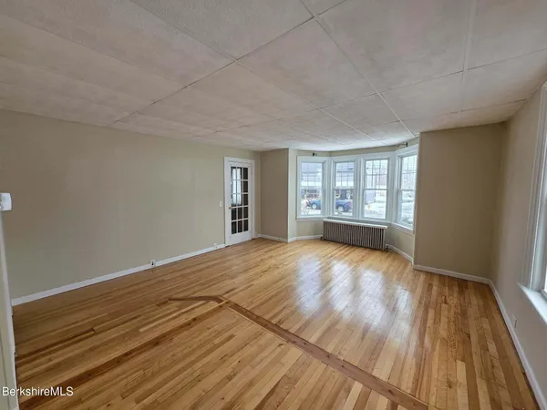 a view of an empty room with a window and wooden floor