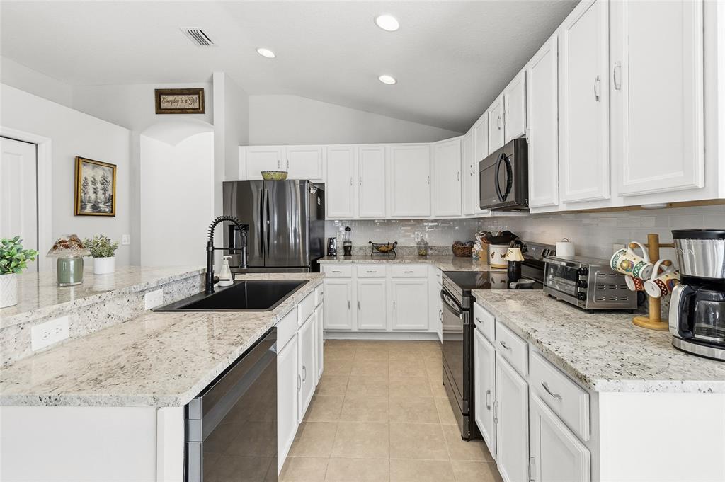 6641 Boulder Run Loop Wesley Chapel, FL 33545 - Photo 11 of 43 a kitchen with stainless steel appliances granite countertop a sink stove and refrigerator