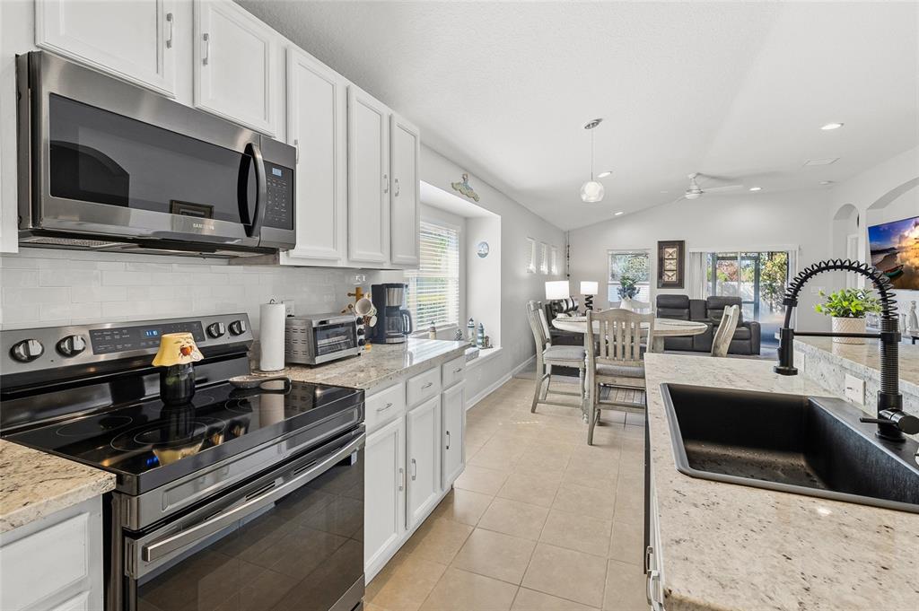 6641 Boulder Run Loop Wesley Chapel, FL 33545 - Photo 12 of 43 a kitchen with stainless steel appliances kitchen island granite countertop a sink and a stove