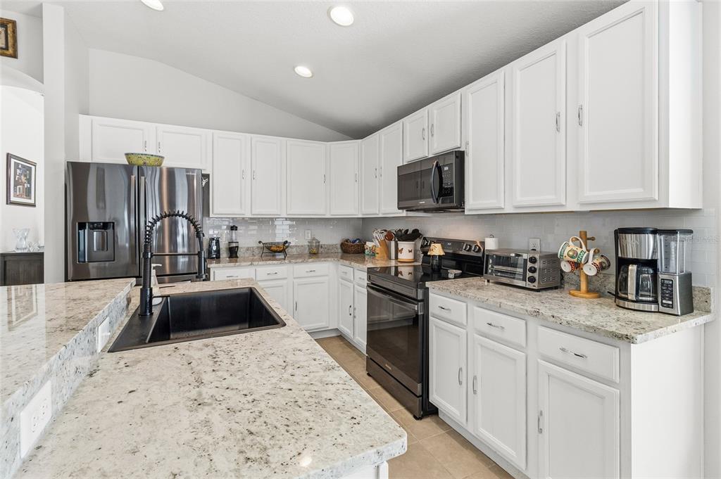 6641 Boulder Run Loop Wesley Chapel, FL 33545 - Photo 10 of 43 a kitchen with granite countertop a sink stainless steel appliances and white cabinets