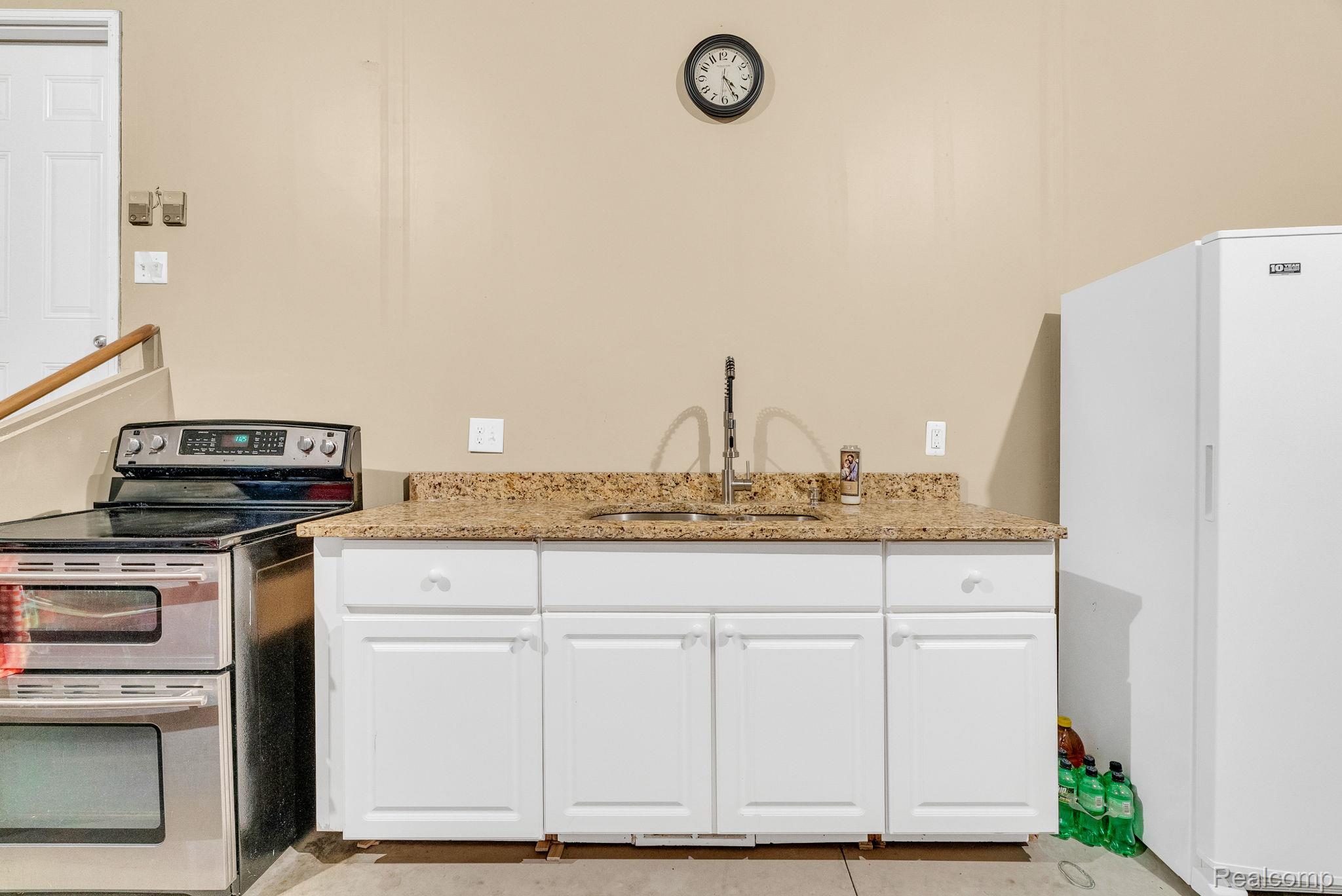 4122 Hawks Nest Road Utica, MI 48317 - Photo 60 of 74 Kitchen featuring double oven range, freestanding refrigerator, white cabinets, light stone counters, and light tile patterned floors
