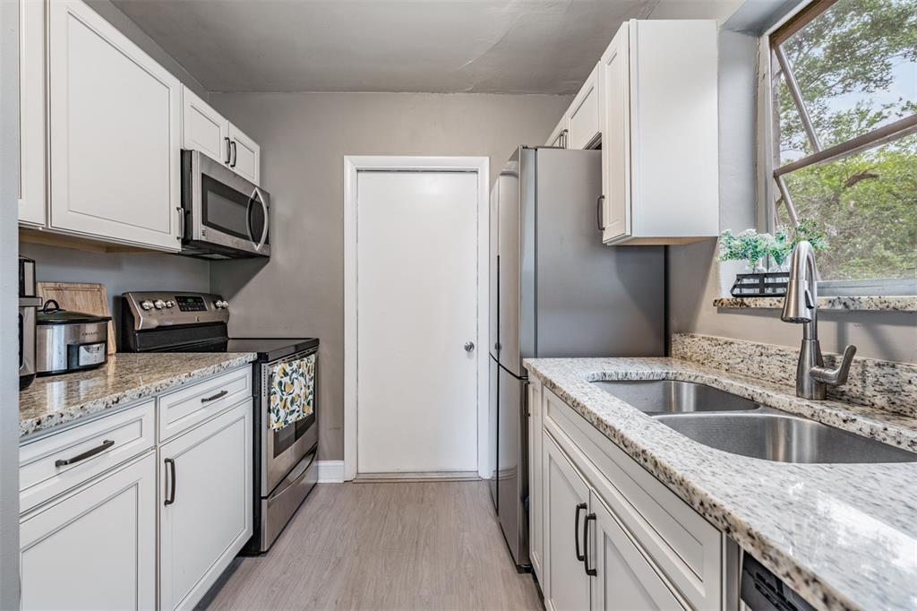 6985 Merrick Lane Spring Hill, FL 34606 - Photo 11 of 15 a kitchen with stainless steel appliances granite countertop a sink stove and microwave