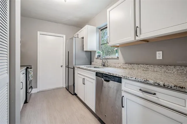 a kitchen with granite countertop a sink stainless steel appliances white cabinets and a counter space