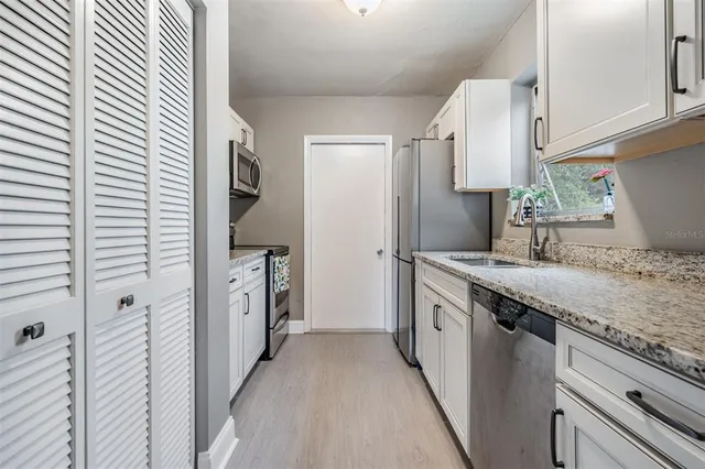 a kitchen with granite countertop a sink and a refrigerator