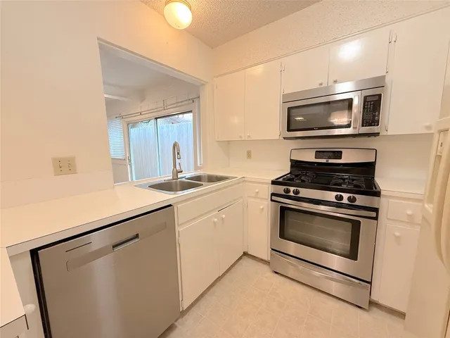 a kitchen with stainless steel appliances white cabinets and stove top oven
