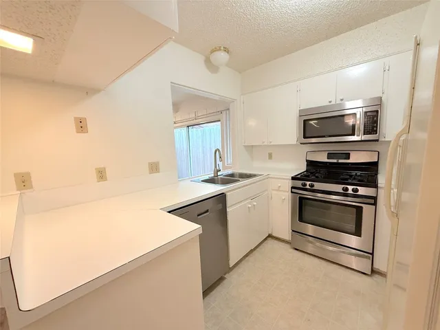 a kitchen with stainless steel appliances a stove microwave and sink