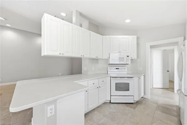 a kitchen with white cabinets and white appliances