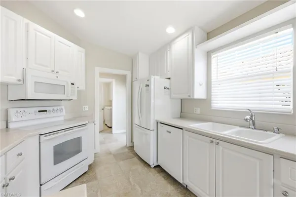 a kitchen with white cabinets and white appliances