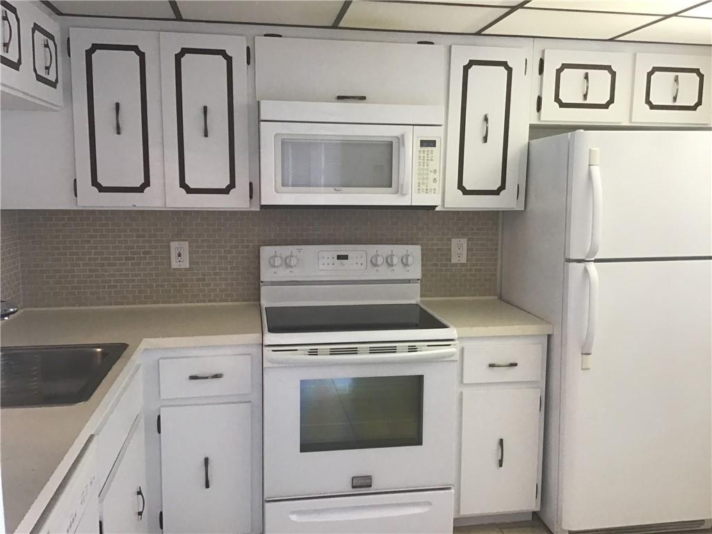 3551 Inverrary Drive, Unit 208 Lauderhill, FL 33319 - Photo 4 of 15 a kitchen with white cabinets and white appliances