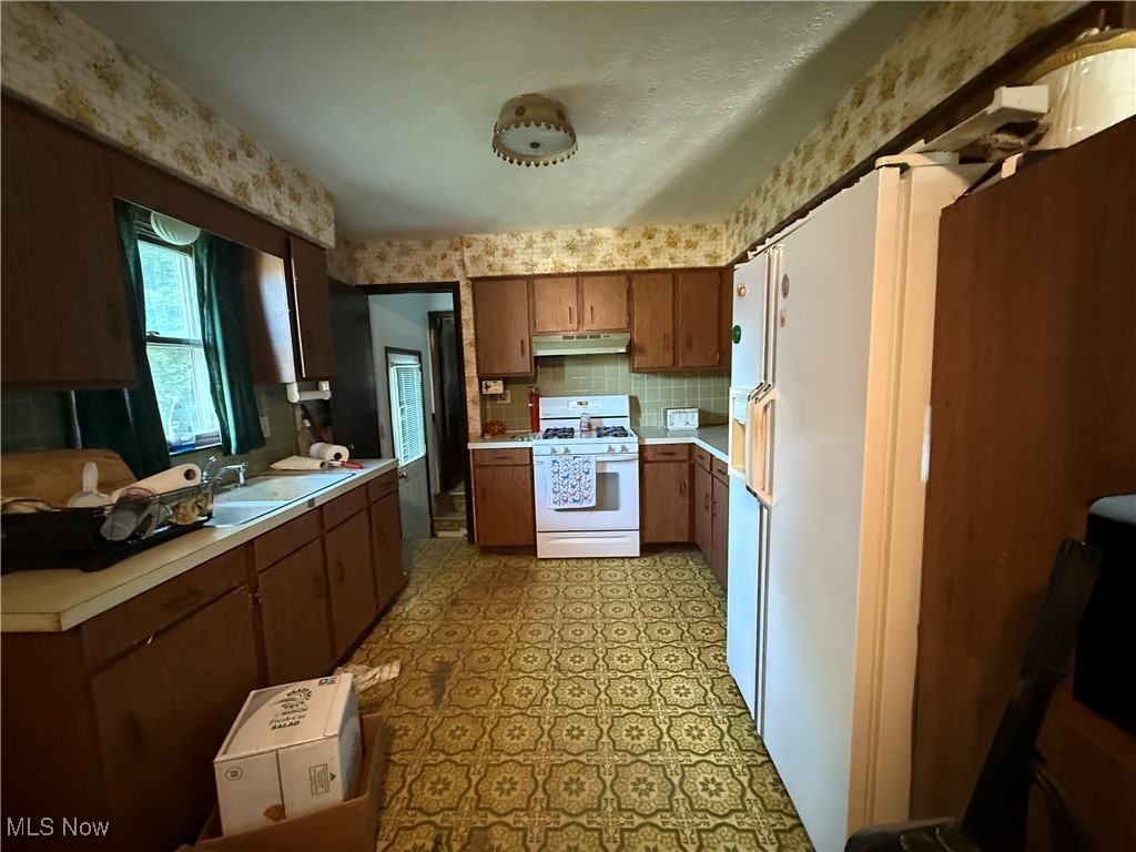 469 Baldwin Road Akron, OH 44312 - Photo 4 of 10 Kitchen with light countertops, white range with gas stovetop, tasteful backsplash, light floors, and brown cabinetry