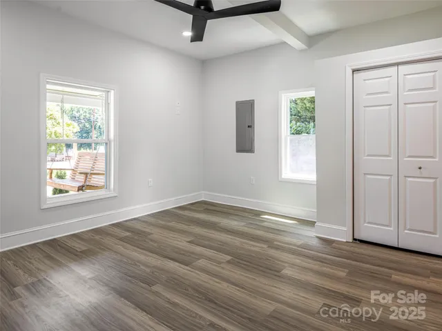 a view of an empty room with wooden floor and a window