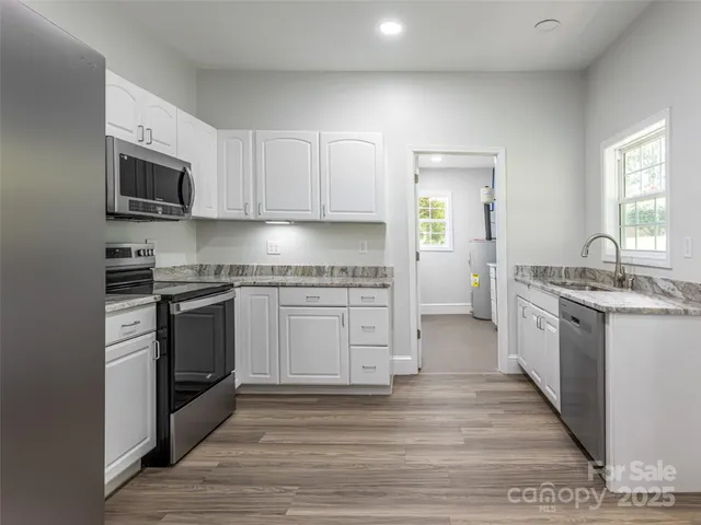 a kitchen with granite countertop a sink cabinets stainless steel appliances and a window