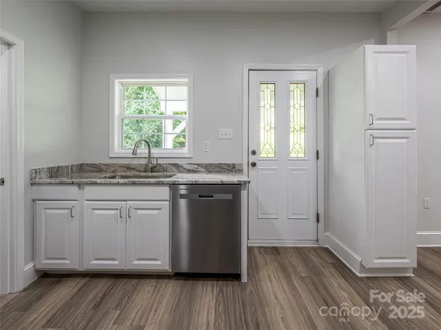 a kitchen with granite countertop wooden floors and white cabinets