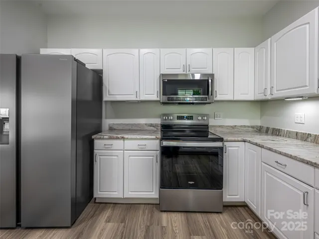 a kitchen with stainless steel appliances granite countertop a refrigerator sink and white cabinets