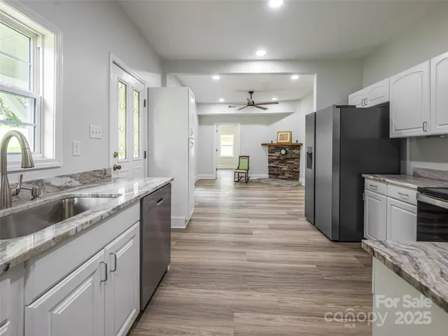 a large kitchen with a center island wooden floor stainless steel appliances and windows