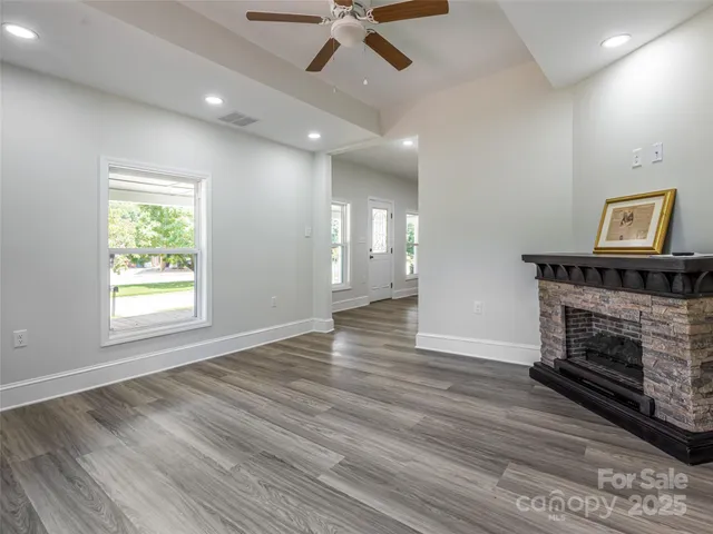 an empty room with wooden floor fireplace and windows