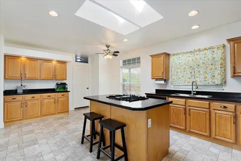 a kitchen with stainless steel appliances granite countertop wooden cabinets a sink a stove a dining table and chairs