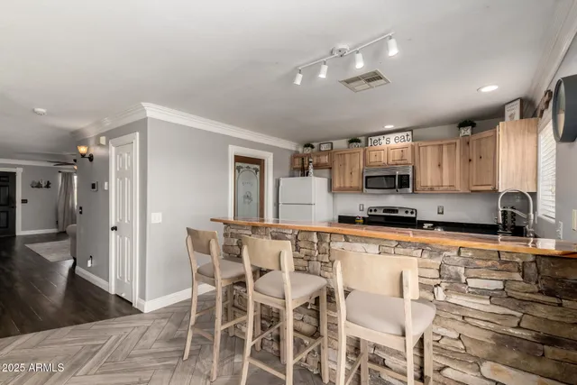 a kitchen with stainless steel appliances granite countertop a stove top oven a sink dishwasher and a refrigerator with wooden floor