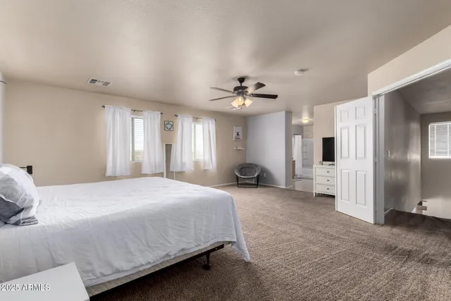 a spacious bedroom with a bed a couch and a chandelier