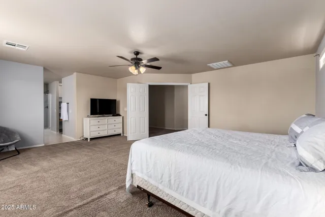 a spacious bedroom with a bed and a tv