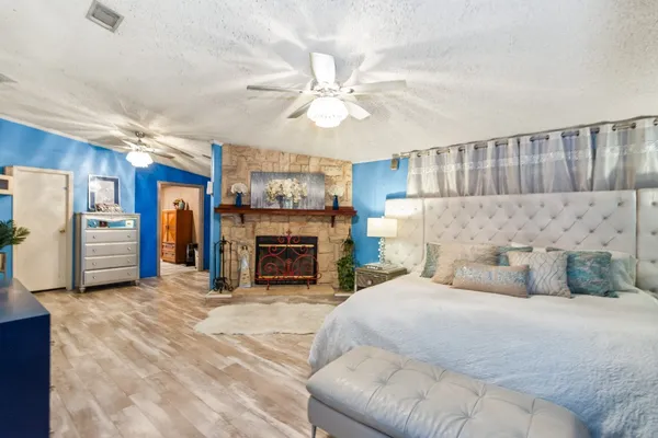 a spacious bedroom with a bed a fireplace and a chandelier