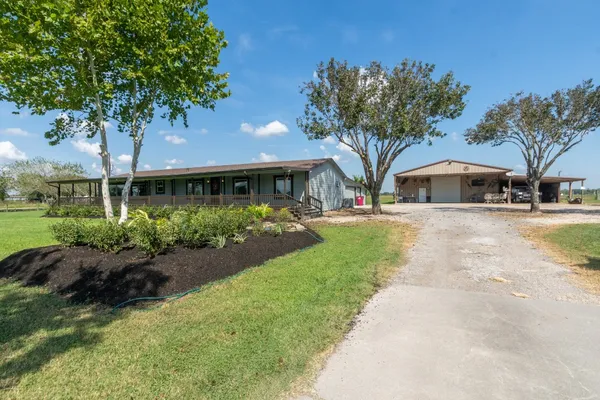 a front view of a house with garden and trees