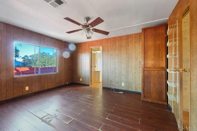 an empty room with wooden floor fan and windows