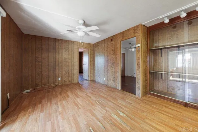 an empty room with wooden floor fan and windows