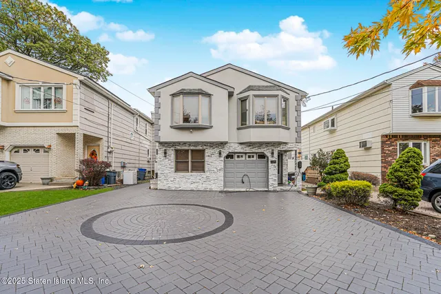 a view of a white house with a small yard and potted plants