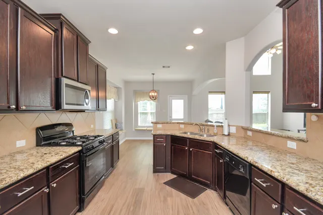 a large kitchen with stainless steel appliances granite countertop a sink stove and cabinets
