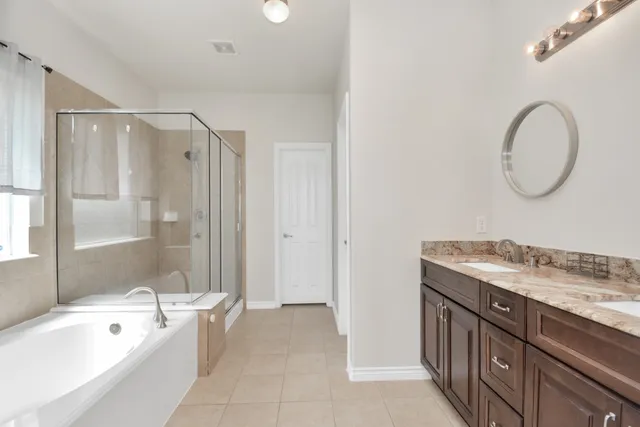 a bathroom with a tub a sink and a large mirror