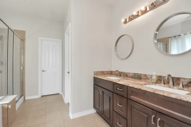 a bathroom with a granite countertop double vanity and a mirror